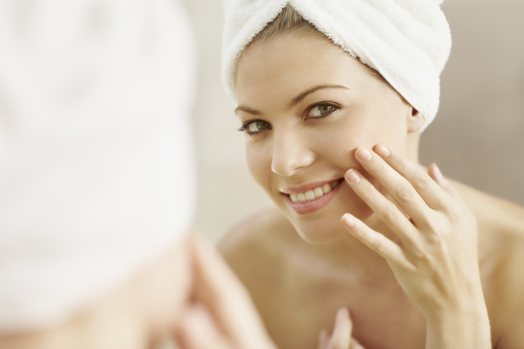 Mirror reflection of a beautiful young woman with clean and soft skin smiling