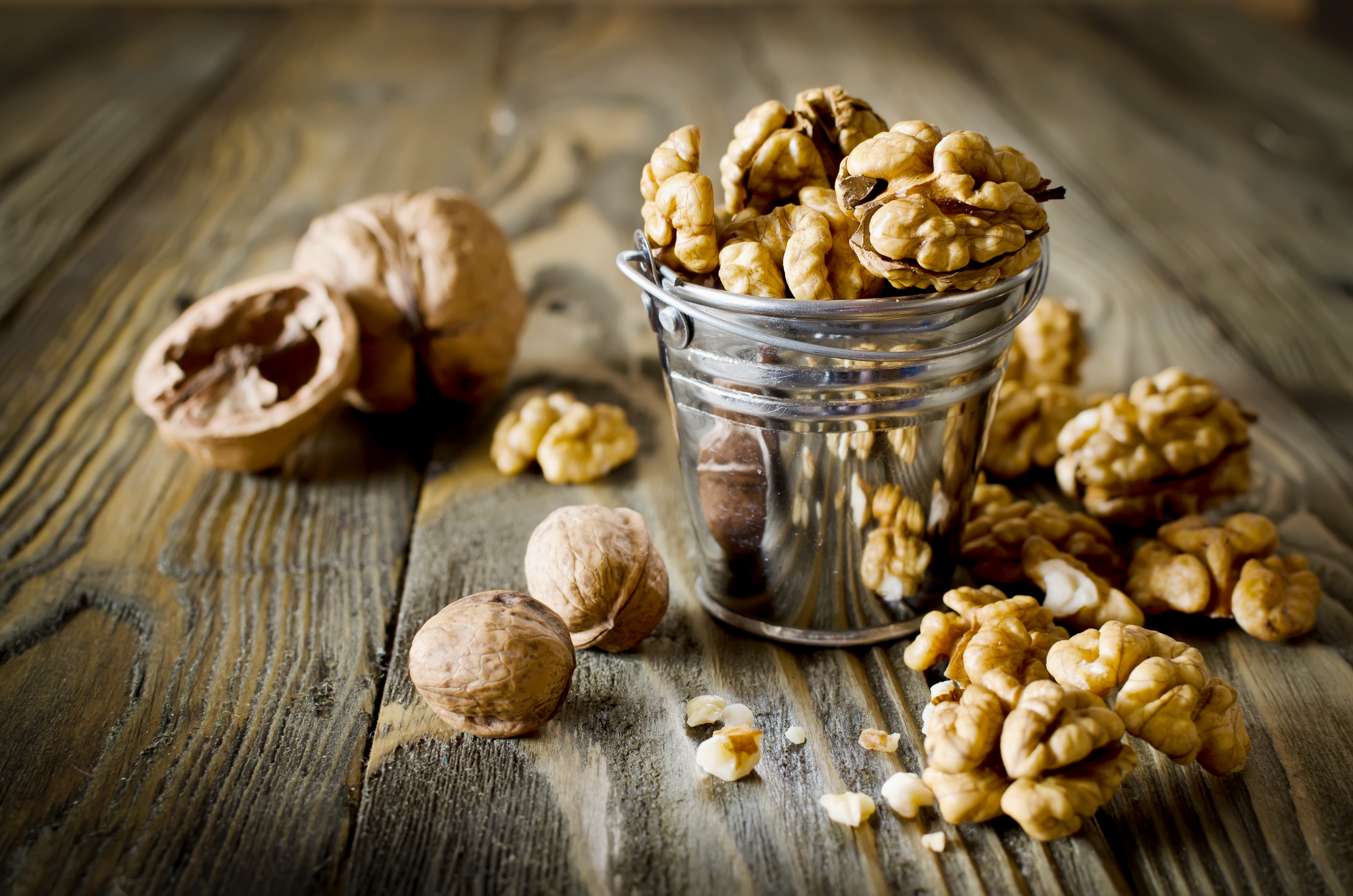 Walnut kernels and whole walnuts on wooden table. Selective Focus